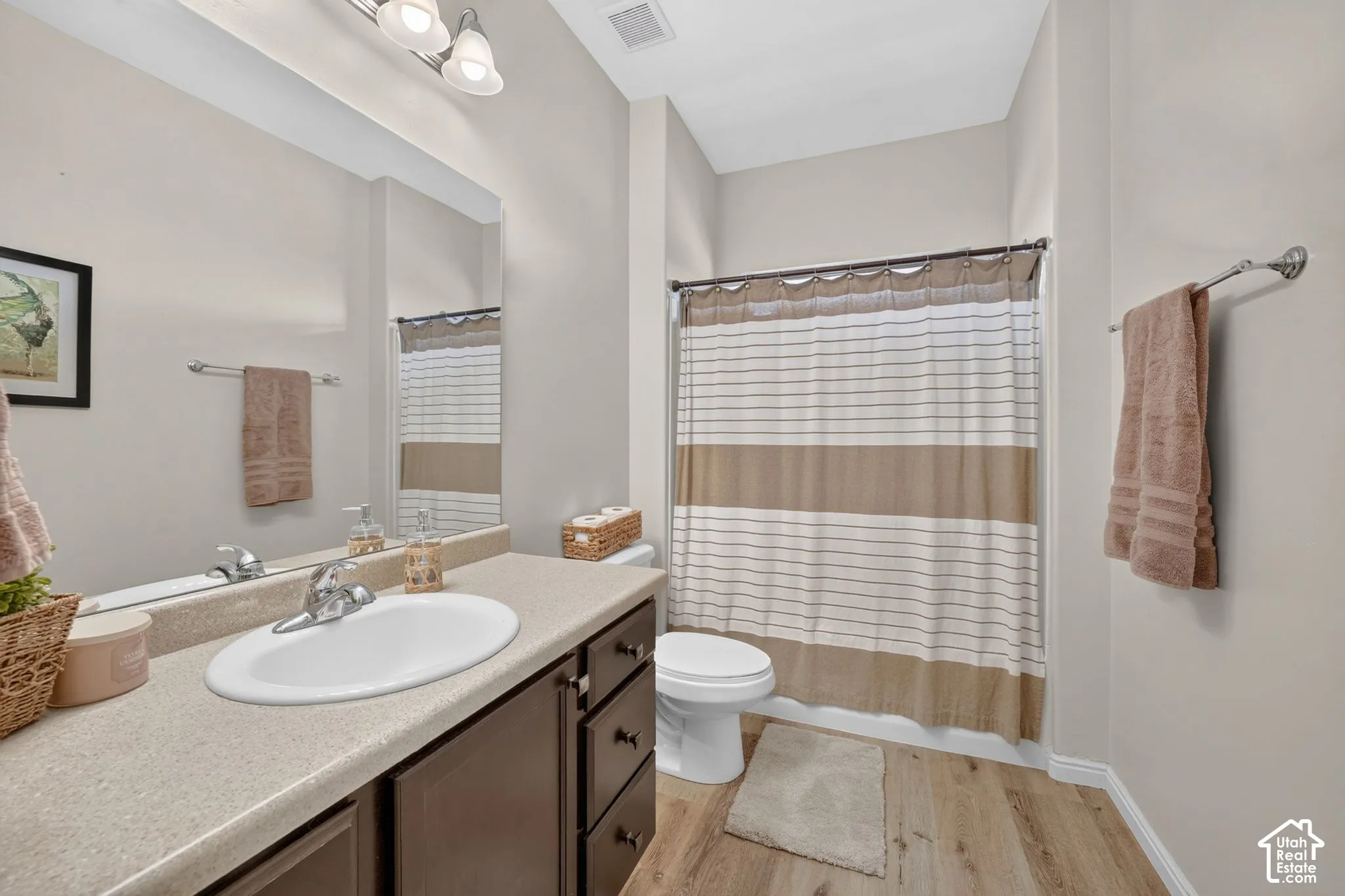 Bathroom featuring a single vanity, wood-finish flooring, a full-size mirror, and an integrated shower/tub