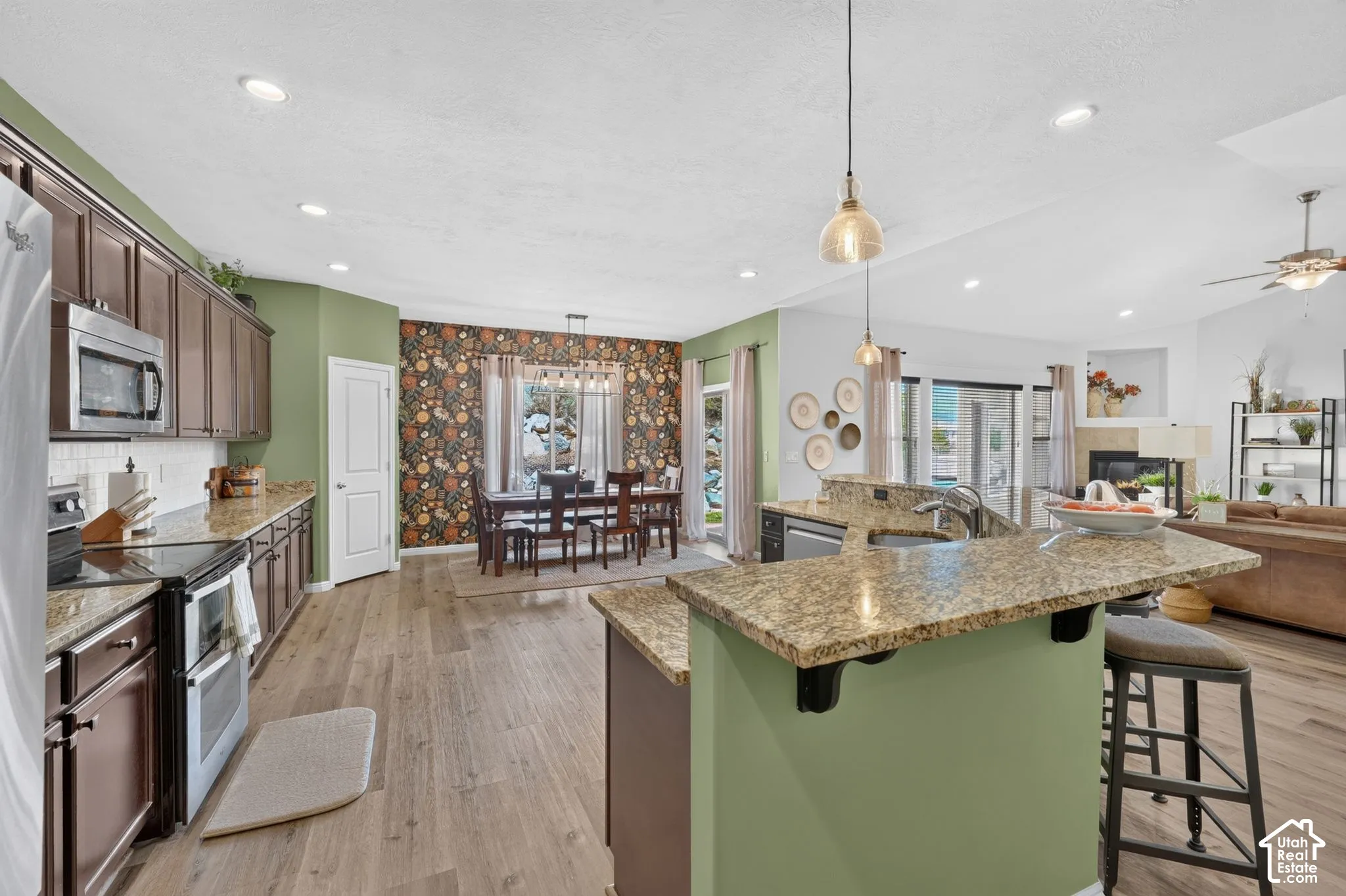 Kitchen featuring wood-finish flooring, stainless steel appliances, granite countertops, and recessed lighting