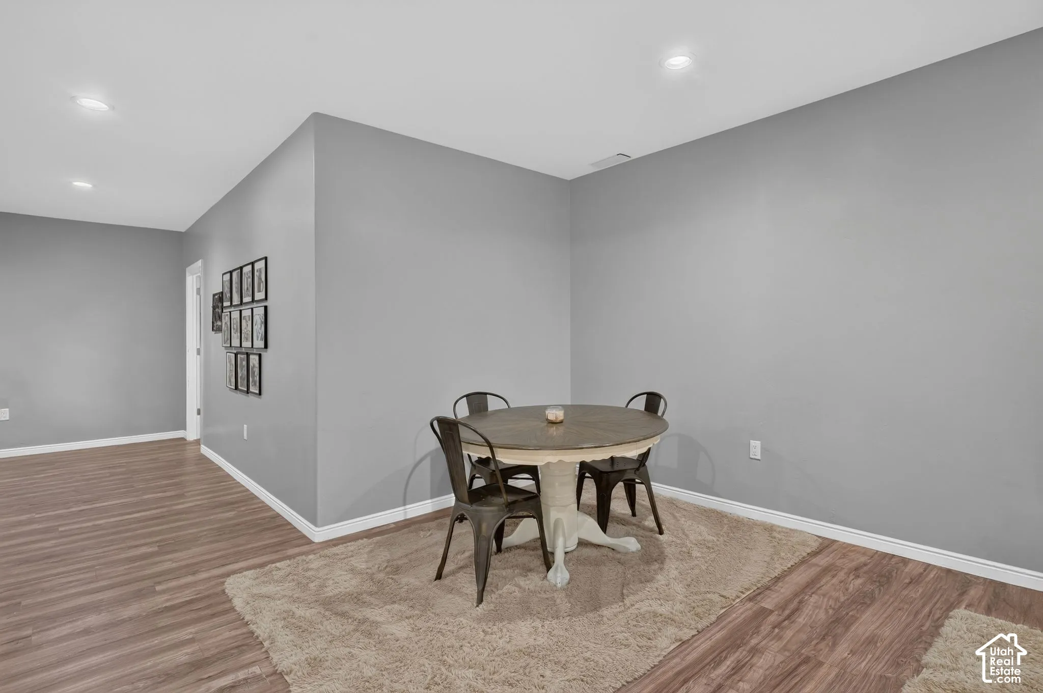 Recessed lighting illuminates the wood-finish flooring and light gray walls