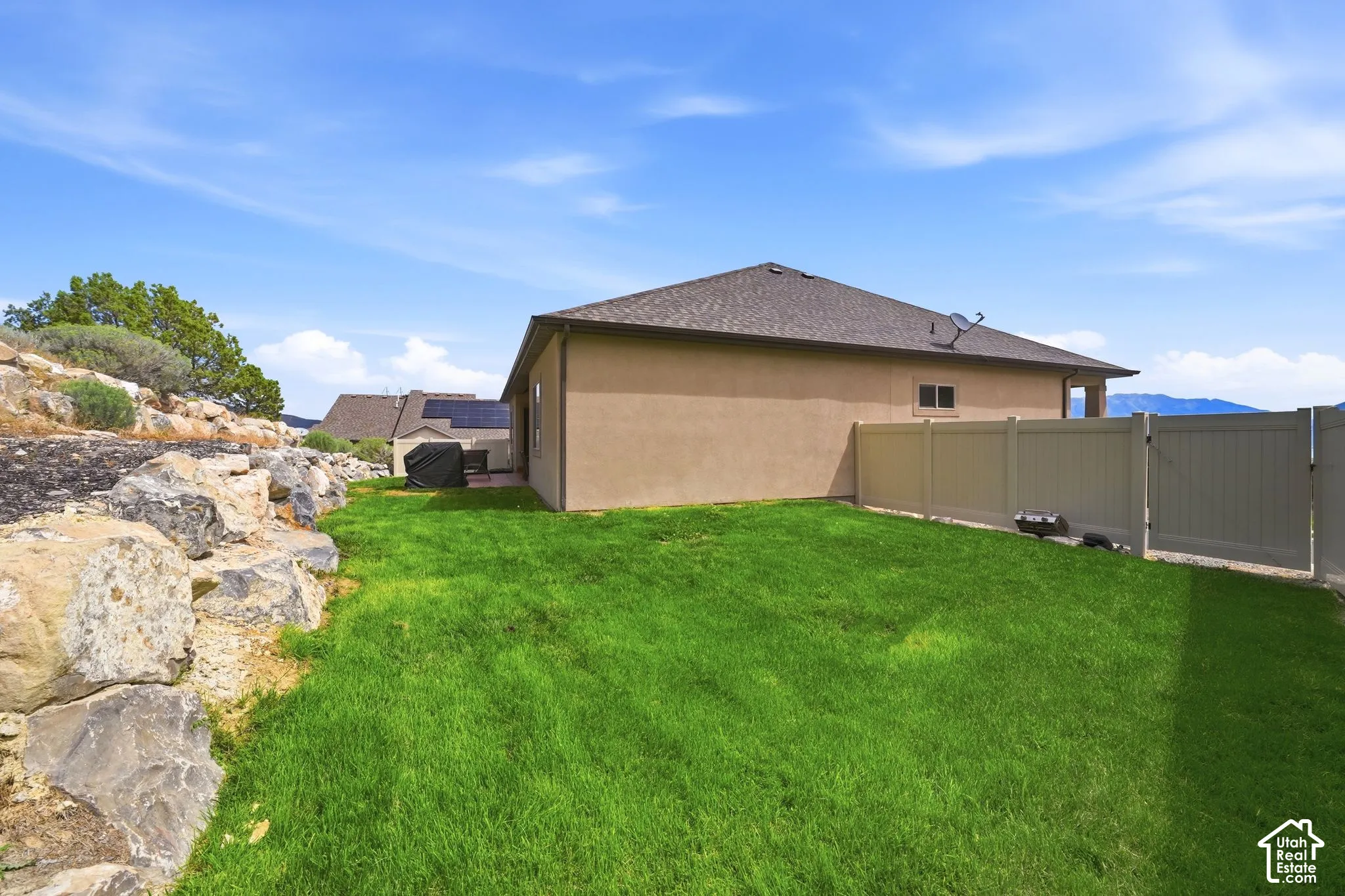Expansive green lawn, durable vinyl fencing, and natural rock landscaping