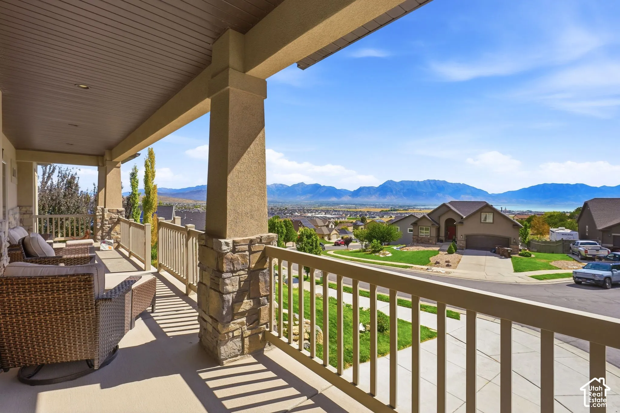 Covered porch with stone-wrapped columns, light-colored railing, and distant mountain scenery