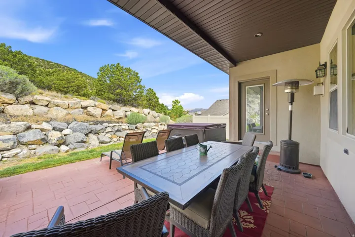 Covered patio featuring stamped concrete flooring, exterior sconce lighting, and a retaining wall with natural stone