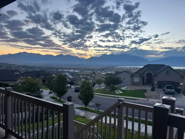 View from the front porch.  Expansive mountain backdrop, distant body of water, and surrounding neighborhood from a property featuring a railing with balusters