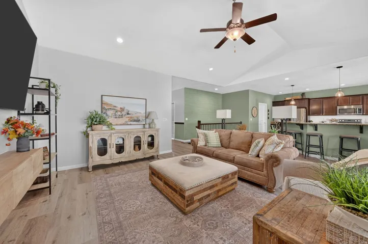 Wood-finish flooring, recessed lighting, and a vaulted ceiling with a ceiling fan