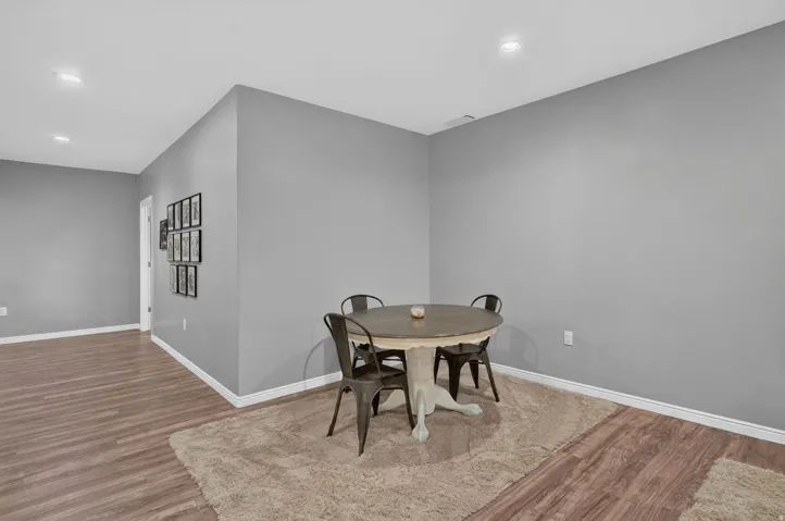 Recessed lighting illuminates the wood-finish flooring and light gray walls