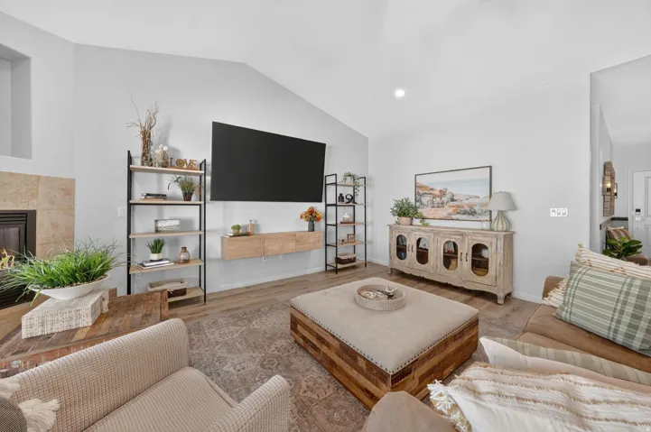 Vaulted ceiling, recessed lighting, tile-surround fireplace, wood-finish flooring, and a floating media console