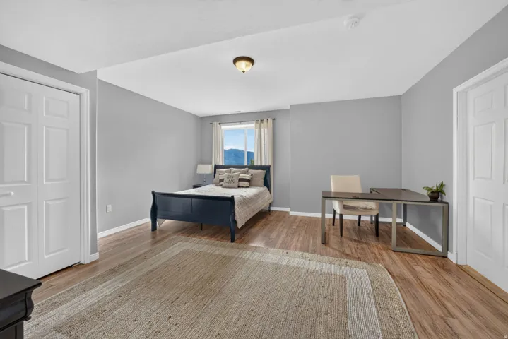 Wood-finish flooring with light gray walls, a window with natural light, and a ceiling-mounted light fixture