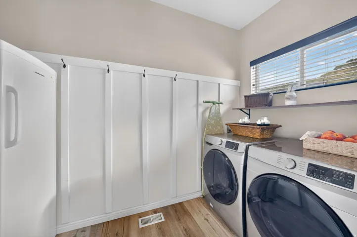 Wood-finish flooring, built-in board and batten paneling, window with blinds, and built-in shelving