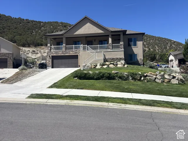 Stucco exterior with stone accents, covered front porch, integrated two-car garage, and a concrete driveway