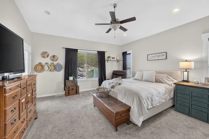 Recessed lighting, ceiling fan, broad window with dark-toned drapes, light-colored carpeting, and a neutral wall palette