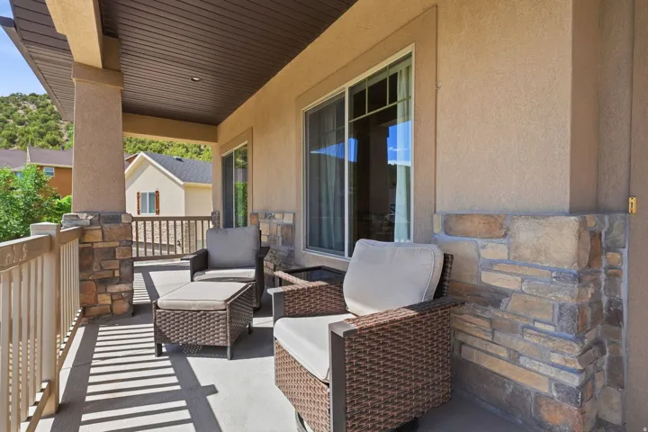 Covered patio featuring stone columns, wood-finish ceiling, stucco exterior, and sliding glass doors