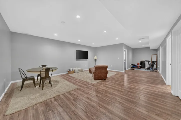 Spacious room featuring wood-finish flooring, recessed lighting, and light gray walls