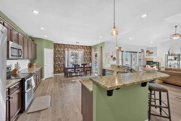 Kitchen featuring wood-finish flooring, stainless steel appliances, granite countertops, and recessed lighting