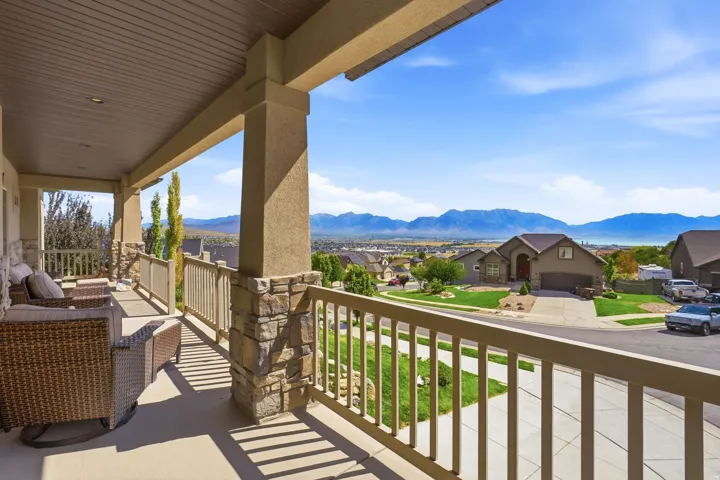 Covered porch with stone-wrapped columns, light-colored railing, and distant mountain scenery
