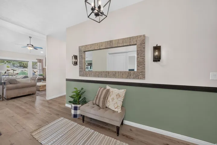 Wood-finish flooring, accent wall with chair rail, recessed ceiling, modern ceiling fan, and contemporary light fixtures