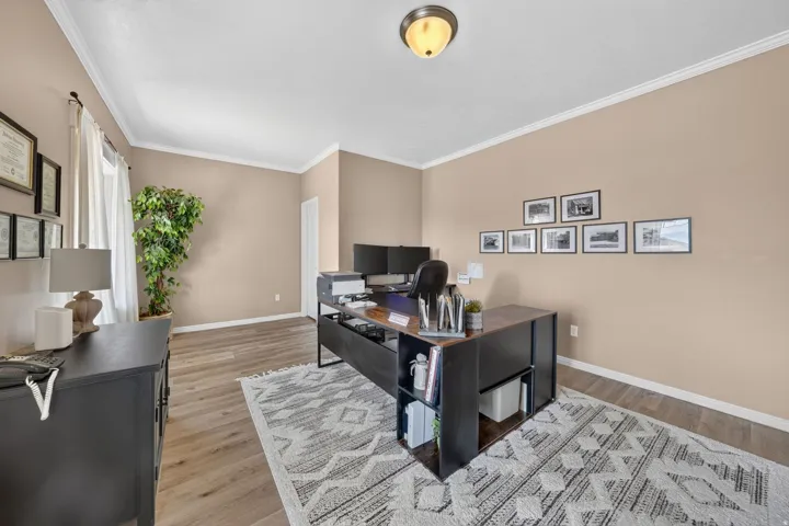 Recessed ceiling light fixture, crown molding, wood-finish flooring, and natural light from a window