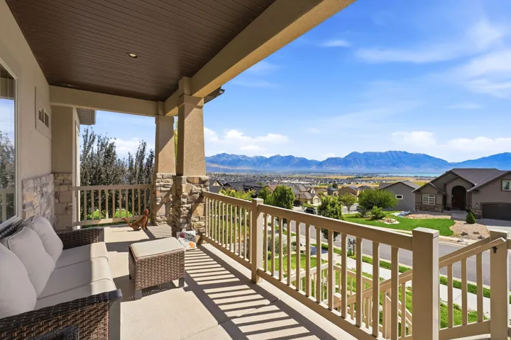 Covered outdoor patio with a planked ceiling, stone column accents, and a wood railing