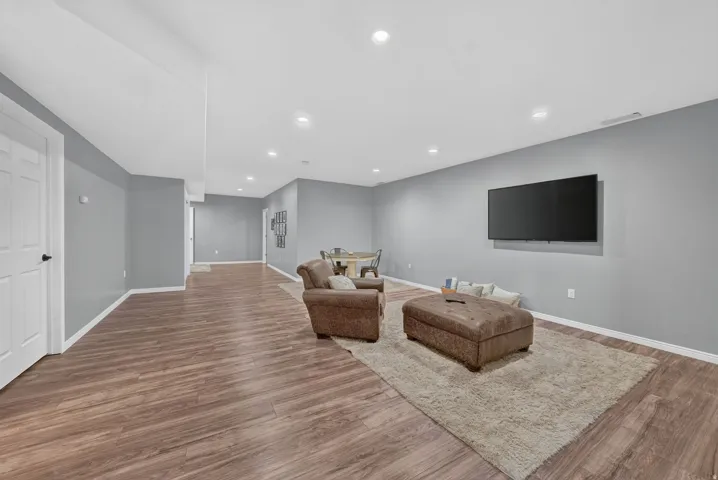 Expansive room featuring wood-finish flooring, recessed lighting, and a neutral wall color