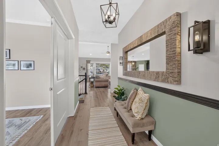 Wood-finish flooring throughout, complemented by a decorative wall mirror with a textured frame