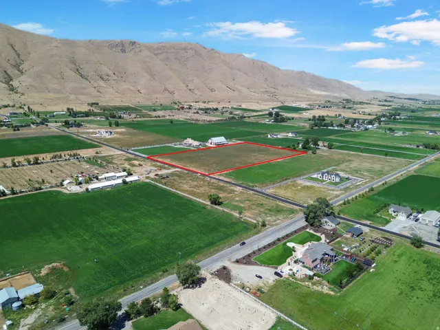 Expansive undeveloped land featuring a verdant field and distant mountain backdrop