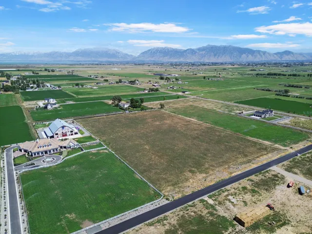 Expansive land parcel with surrounding agricultural fields, distant mountains, and partially paved roads