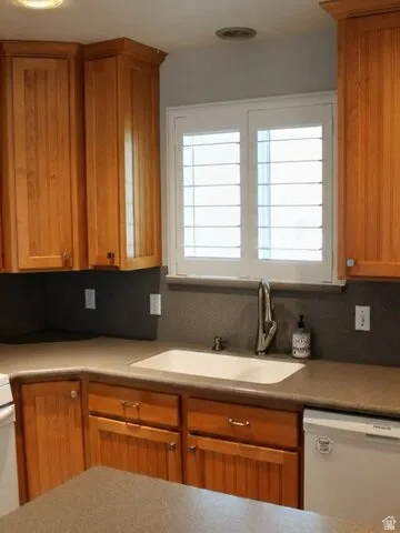 Wood cabinetry with crown molding, solid surface countertops, integrated sink, and white plantation shutters