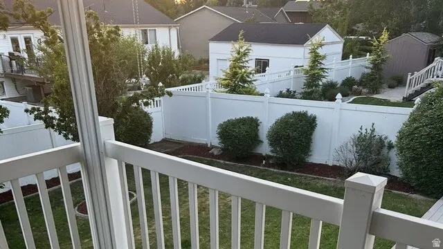 Expansive backyard featuring a manicured lawn, established shrubs, and white panel fencing