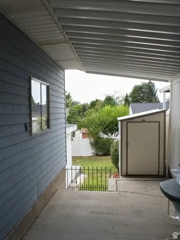 Covered concrete patio with horizontal plank siding and a shed