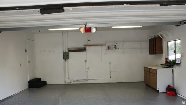 Spacious garage featuring a finished floor, built-in cabinetry, and integrated shelving