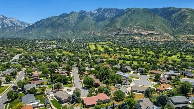 Expansive residential area with mountain backdrop, featuring a golf course, mature trees, and cul-de-sac streets