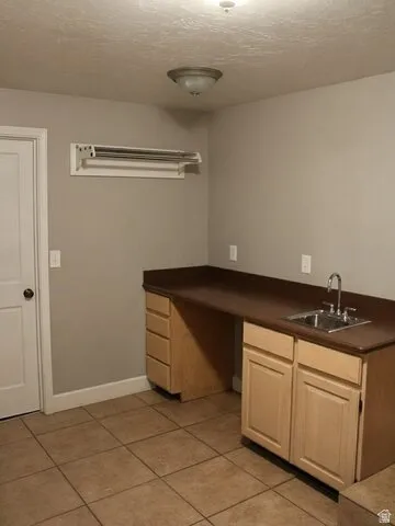 Built-in cabinetry with a sink, durable countertop, and tile flooring