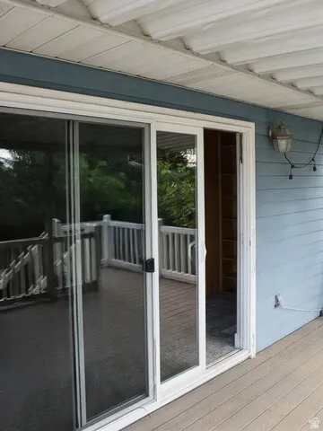 Expansive outdoor deck with a sliding glass door, white railing, and wall-mounted exterior lighting