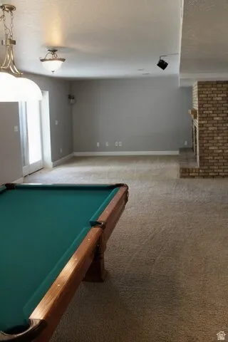 Carpeted flooring, brick fireplace with mantel, recessed lighting, and wall-mounted light fixtures