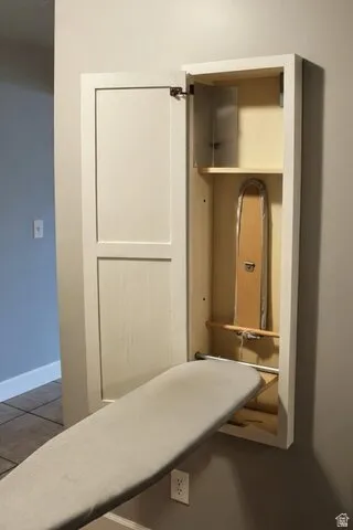 Built-in ironing board cabinet with white shaker-style door and integrated shelving