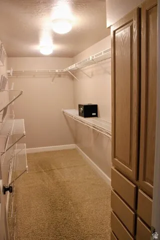 Walk-in closet featuring built-in cabinetry, wall-mounted shelving, and recessed lighting