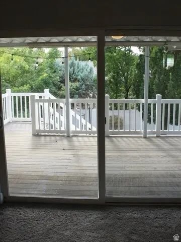 Sliding glass doors opening to an exterior wood-finish deck with white railings