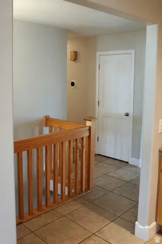 Tile flooring, wood-finish stair railing, and a crisp white door
