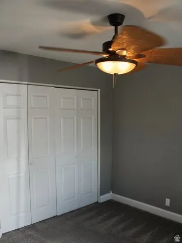 Ceiling fan with integrated lighting, bi-fold closet doors, wall-to-wall carpeting, and neutral wall paint