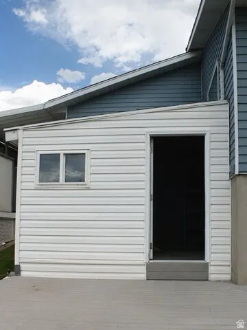 Exterior featuring light-colored siding, a dark trim door, and a gray composite deck