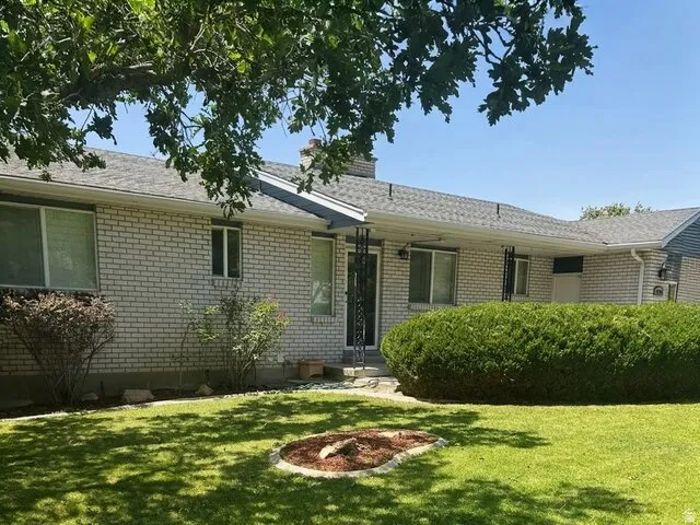 Brick exterior with a gray shingle roof, complemented by a manicured lawn and mature landscaping