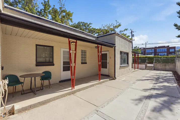 Low-maintenance outdoor living area with covered unit entries, concrete patio space for seating, and a wide walkway extending through the property.