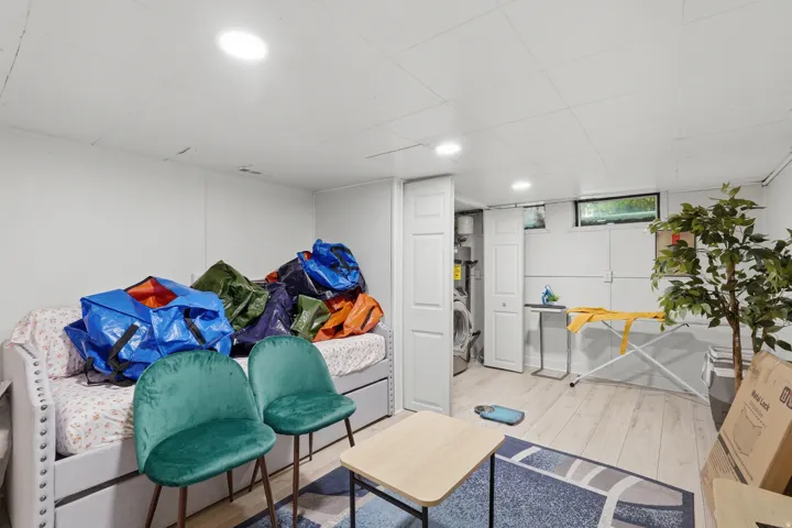[Unit 2] Flexible lower-level bonus space featuring light wood-look flooring, bright recessed lighting, and access to laundry facilities.