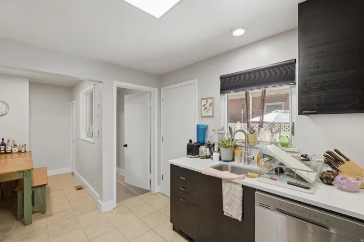 [Unit 1] Efficient modern kitchen equipped with stainless steel appliances, dark contemporary cabinetry, solid surface counter space, and tiled flooring.