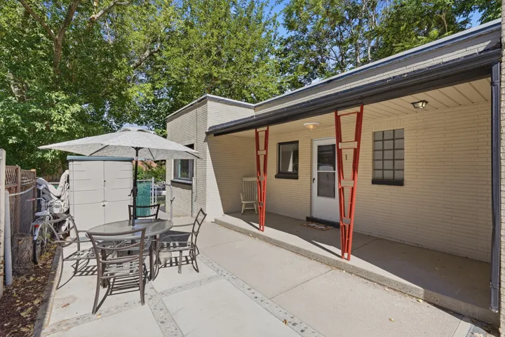 Shared outdoor courtyard space featuring dedicated covered entryways, patio dining area with umbrella, and convenient exterior storage shed.