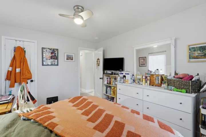 [Unit 1] Comfortable bedroom featuring neutral tones, an updated overhead ceiling fan, and room for a full dresser setup and storage.
