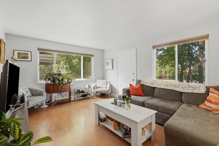 [Unit 1] Bright and inviting living space featuring sleek wood-look flooring, neutral paint, and an open layout with excellent natural light.