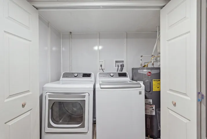 [Unit 1] Dedicated laundry space featuring side-by-side full-size washer and dryer hookups with clean, closed-door storage and easy water heater access.