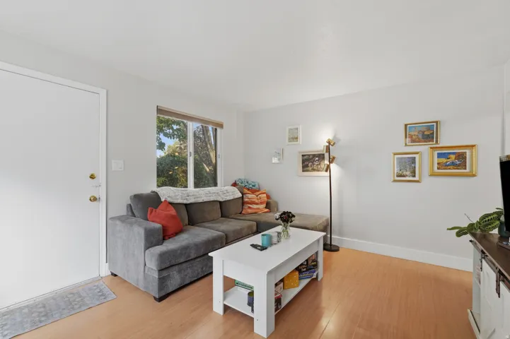 [Unit 1] Bright and inviting living space featuring sleek wood-look flooring, neutral paint, and an open layout with excellent natural light.