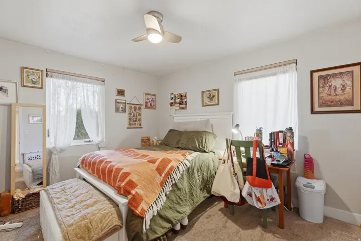 [Unit 1] Comfortable bedroom featuring neutral tones, an updated overhead ceiling fan, and room for a full dresser setup and storage.