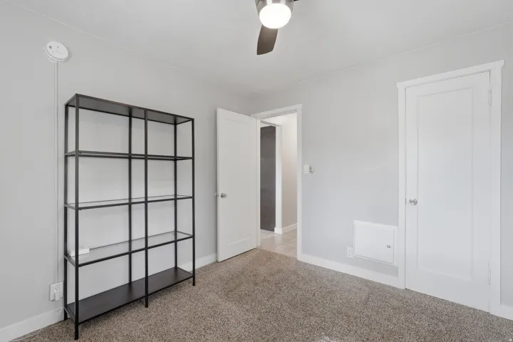 [Unit 3] Functional bedroom space with clean carpet, contemporary lighting, and well-positioned closet storage access.